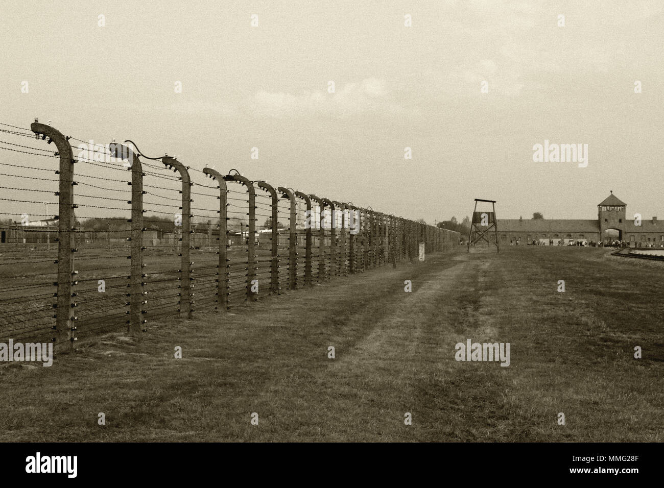 AUSCHWITZ, POLAND, OCTOBER 12, 2013: Fence and watchtower at concentration camp at Auschwitz Birkenau KZ, black white and beige duplex processing photography with image noise effect, Poland Stock Photo
