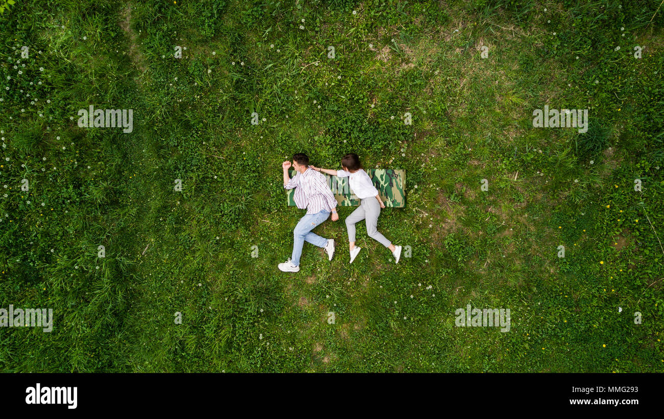 above view of young couple holding hands while lying on the grass Stock Photo