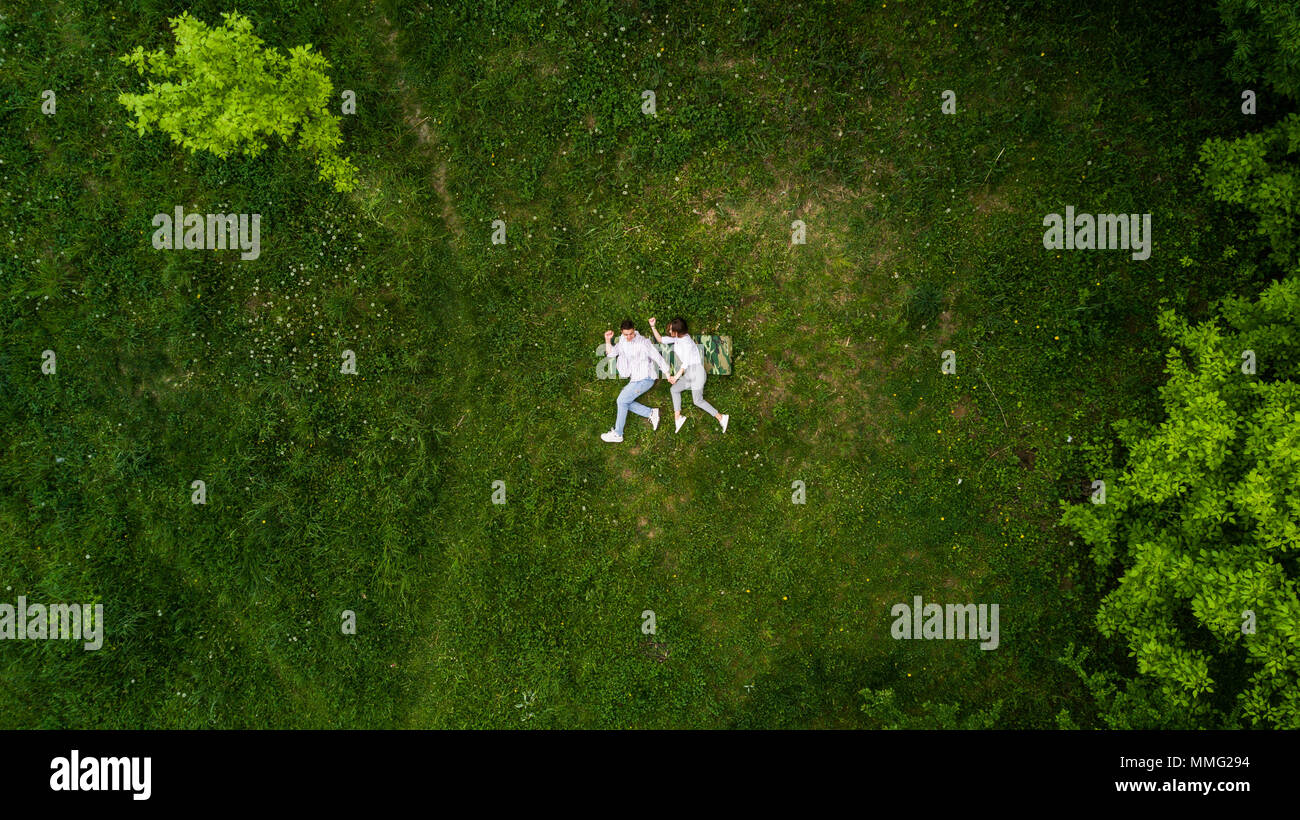 above view of young couple holding hands while lying on the grass Stock Photo