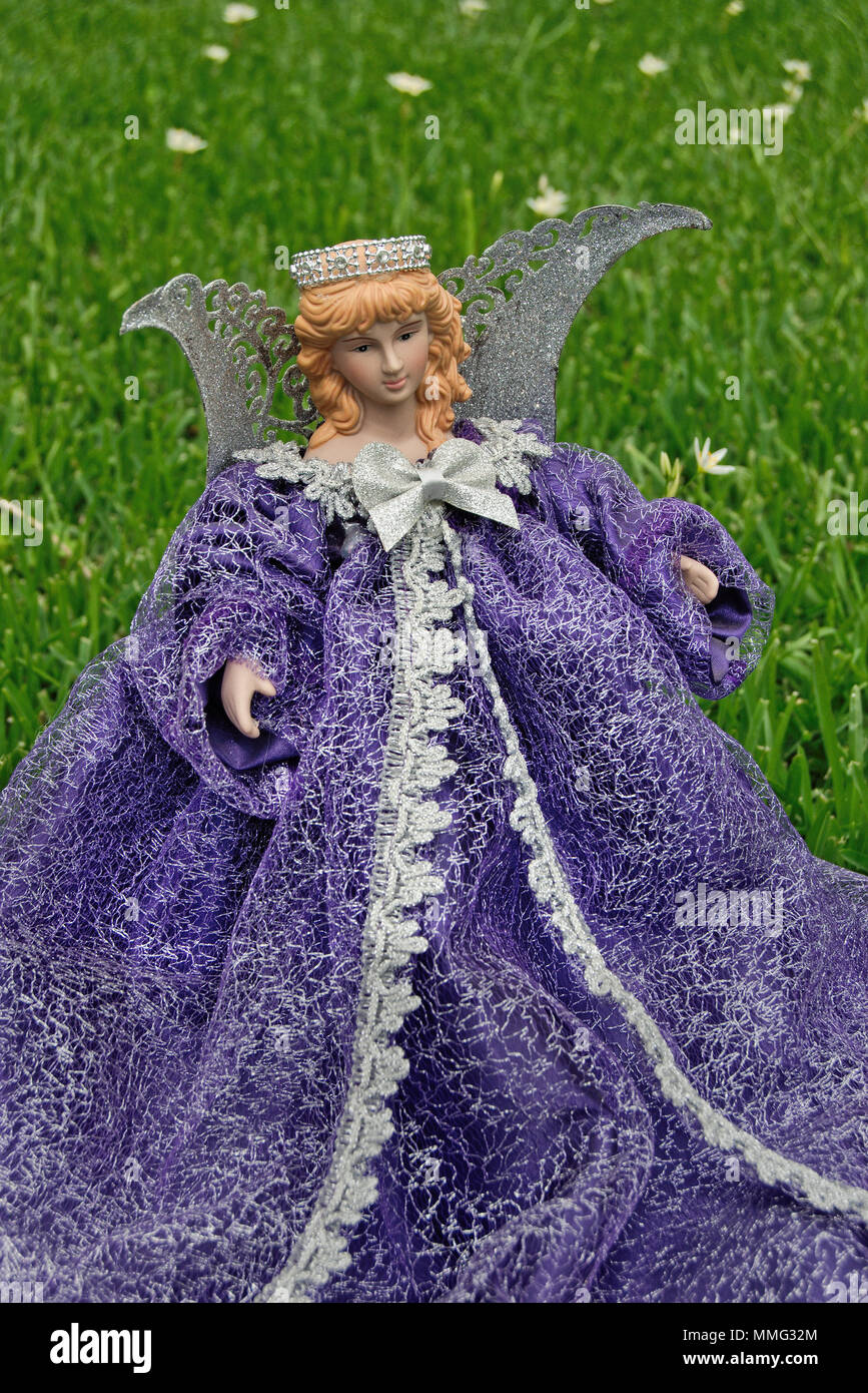 Angelic porcelain doll with purple dress and wings in grass Stock Photo -  Alamy