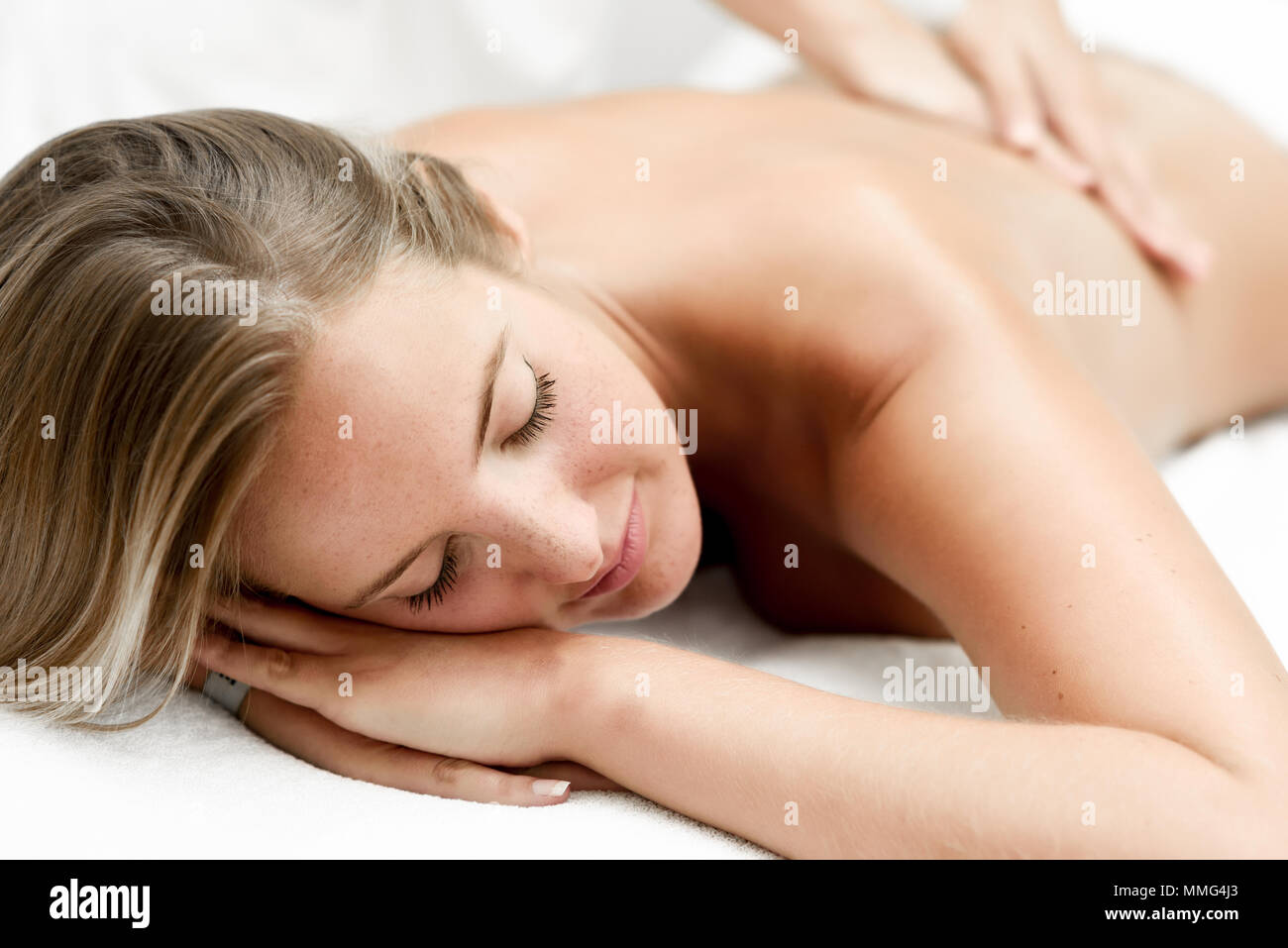 Young blond woman having massage in the spa salon. Massage and body care. Body massage treatment. Stock Photo