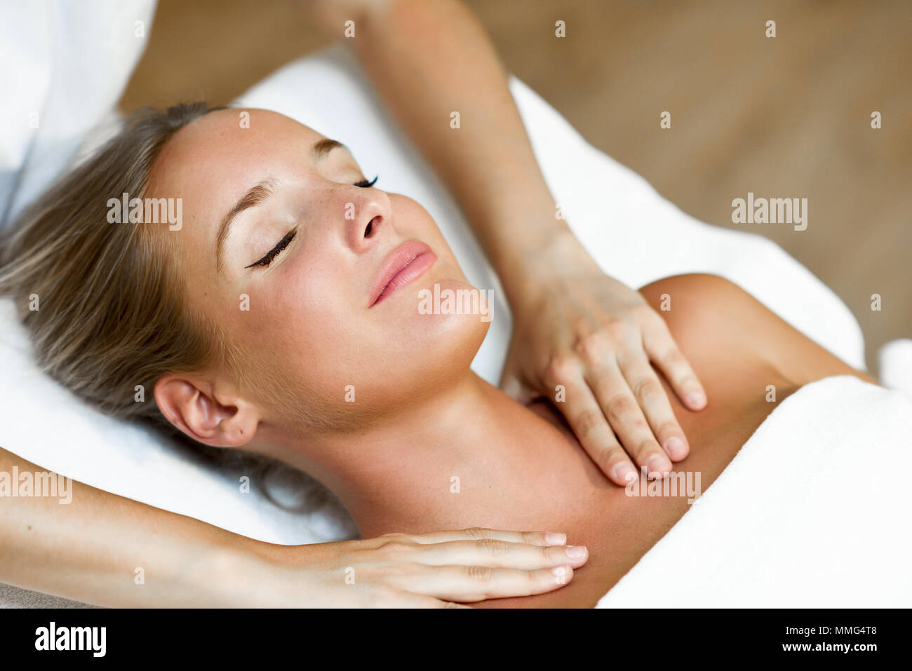 Young blond woman receiving a head massage in a spa center with eyes closed and smiling. Female patient is receiving treatment by professional therapi Stock Photo