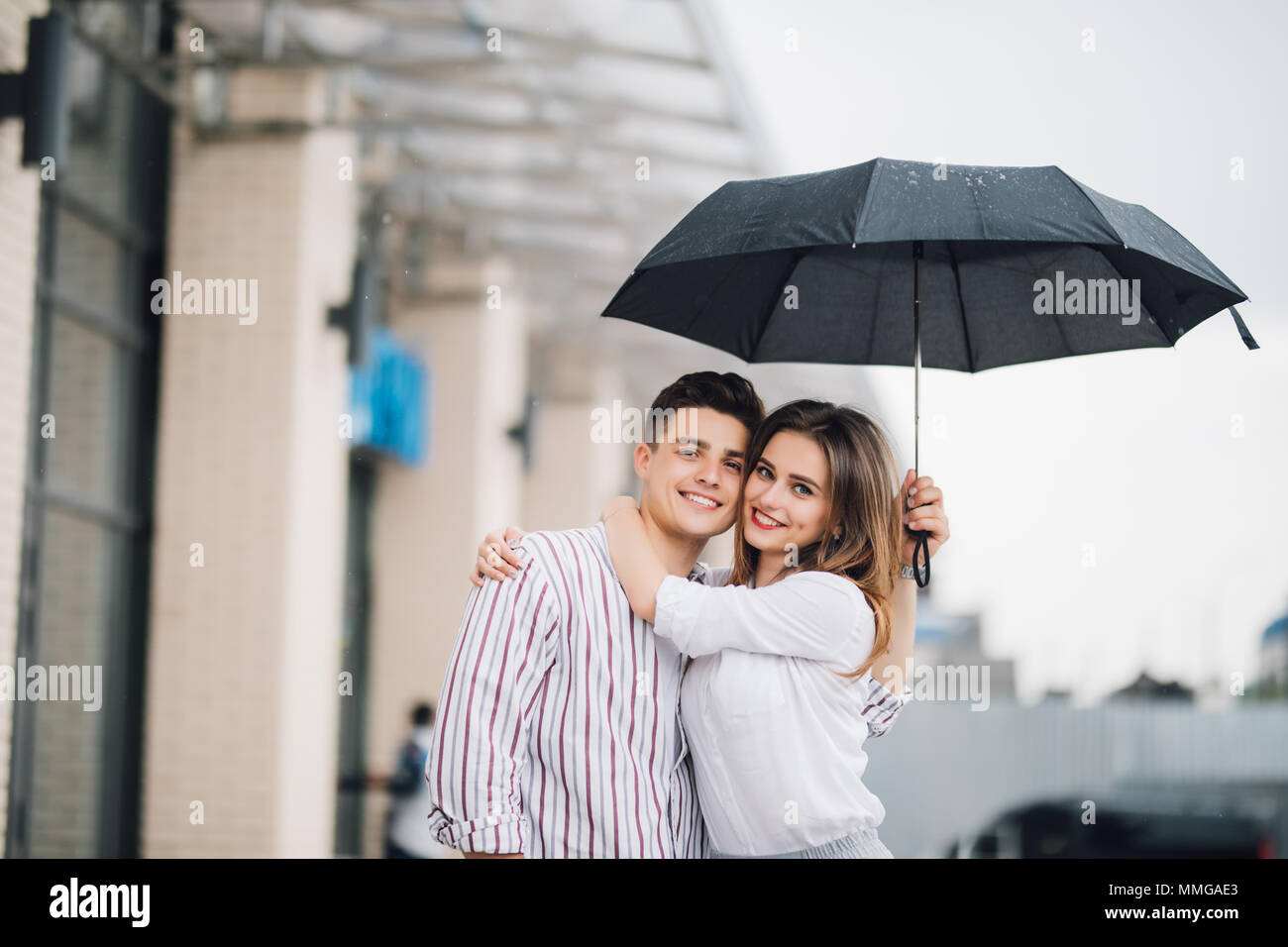 Happy young couple embracing under umbrella in rain day. Couple in love  relationships concept and idea Stock Photo - Alamy
