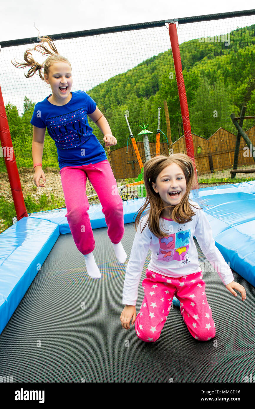 Happy girls jumping high on a trampoline on a sunny day outdoors Stock  Photo - Alamy