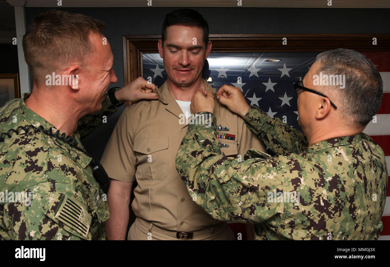 NORFOLK, Va. (May 7, 2018) -- Lt. j.g. Corey T. Jones (center), assigned to USS Gerald R. Ford's (CVN 78) media department, is pinned to his current rank by Chief Mass Communication Specialist Bryan Weyers (left) and Lt. Cmdr. Anthony Falvo (right), Ford's public affairs officer, during a promotion ceremony held onboard. (U.S. Navy photo by Mass Communication Specialist 3rd Class Liz Thompson) Stock Photo