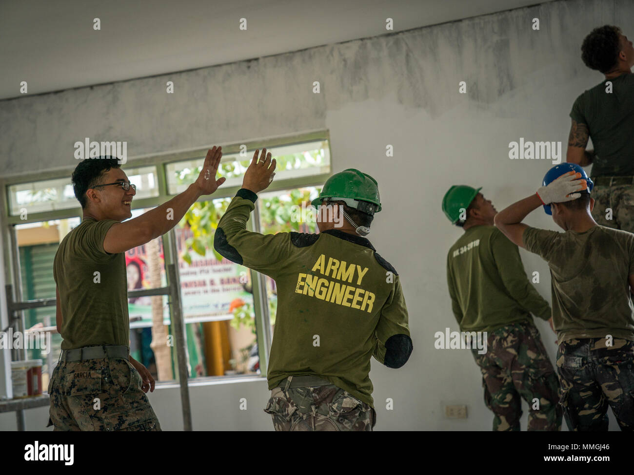 U.S. Marine Corps Sgt. Andreas Garcia (left) and Philippine Army Pfc. Dickson Hermoso (center) high five each other during construction in support of Exercise Balikatan at Calangitan Elementary School in Capas, Tarlac, Philippines, May 6, 2018. Garcia is a combat engineer with Alpha Company, 9th Engineer Support Battalion, and is a 23-year-old native of Chicago, Illinois. Hermoso is an electrician with 522nd Engineering Construction Battalion, 51st Engineering Brigade, and is a 30-year-old native of North Cotabato, Philippines. Exercise Balikatan, in its 34th iteration, is an annual U.S.-Phili Stock Photo