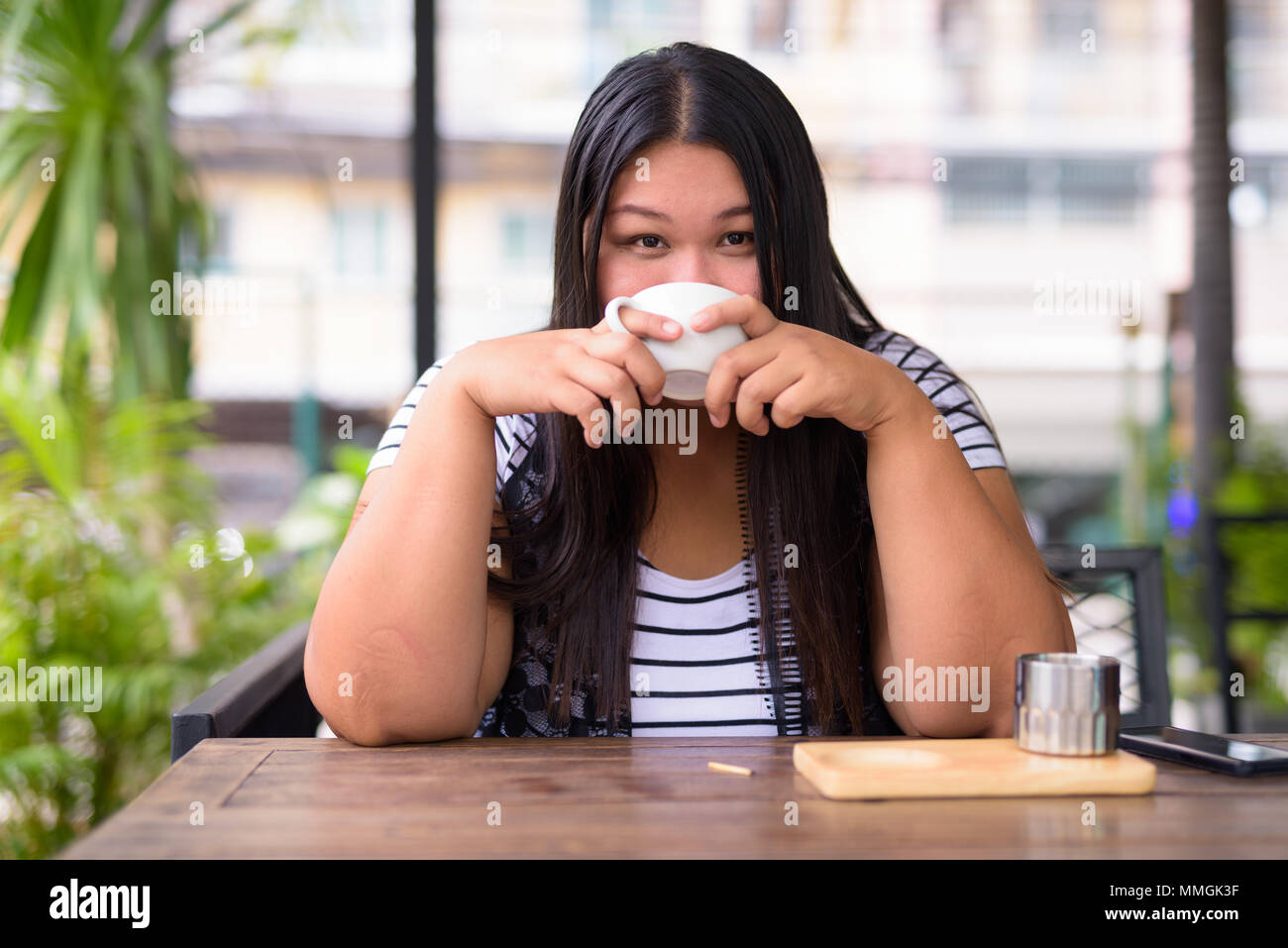 Beautiful overweight Asian woman relaxing at the coffee shop Stock Photo