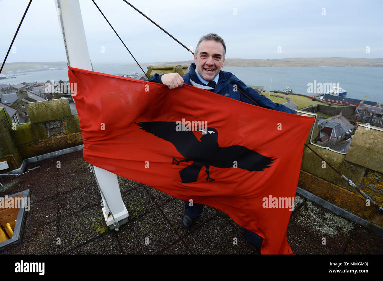 Caretaker of the Lerwick town hall putting up the Raven Banner flag for the Lerwick Up Helly Aa celebrations on the last Tuesday of January Stock Photo