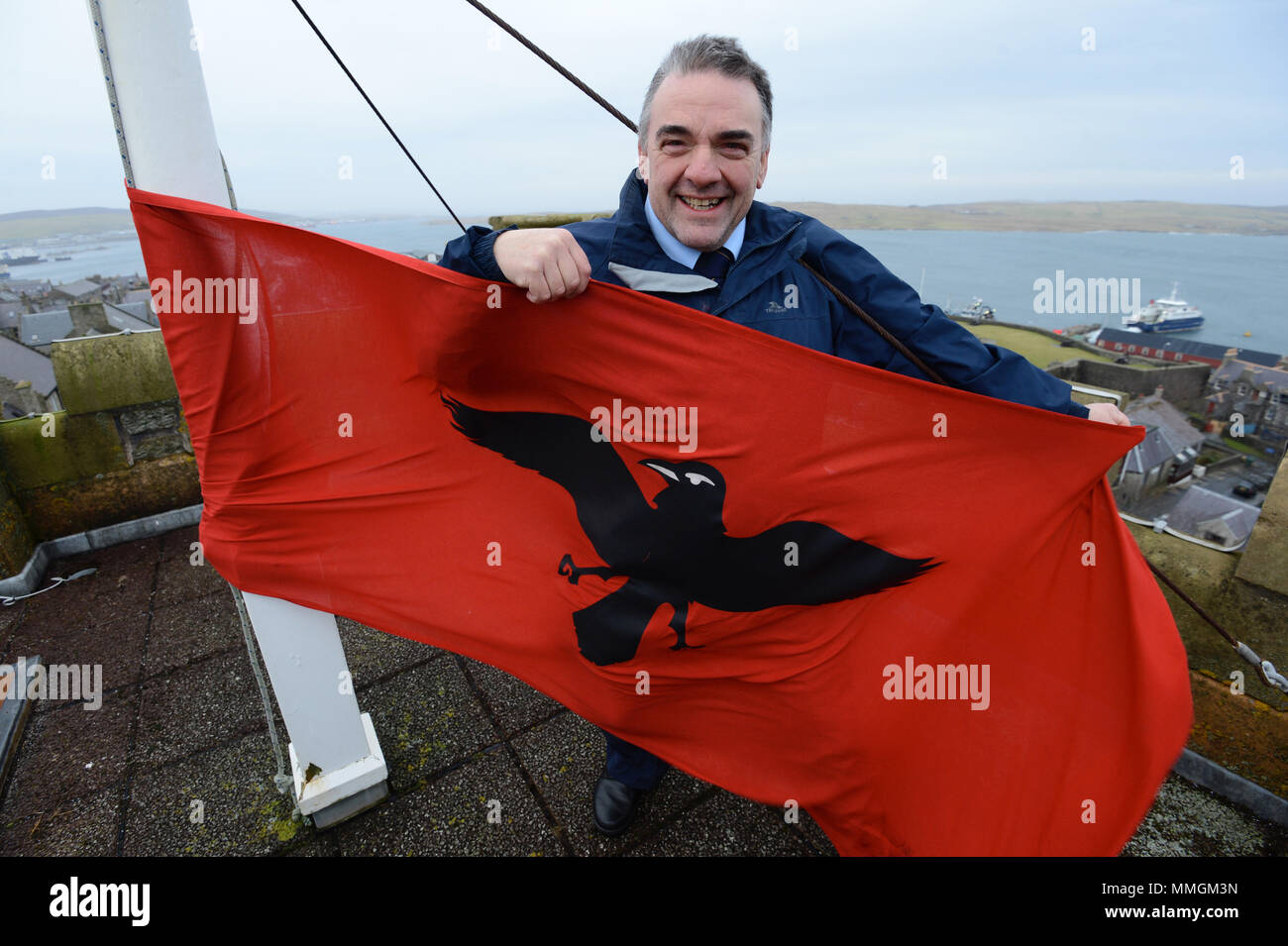 Caretaker of the Lerwick town hall putting up the Raven Banner flag for the Lerwick Up Helly Aa celebrations on the last Tuesday of January Stock Photo