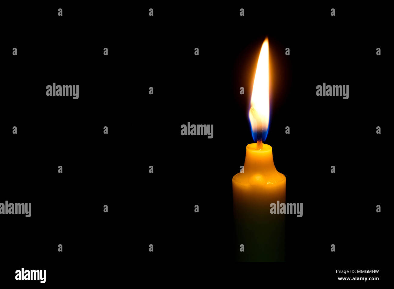 One light candle burning brightly on black background. Stock Photo