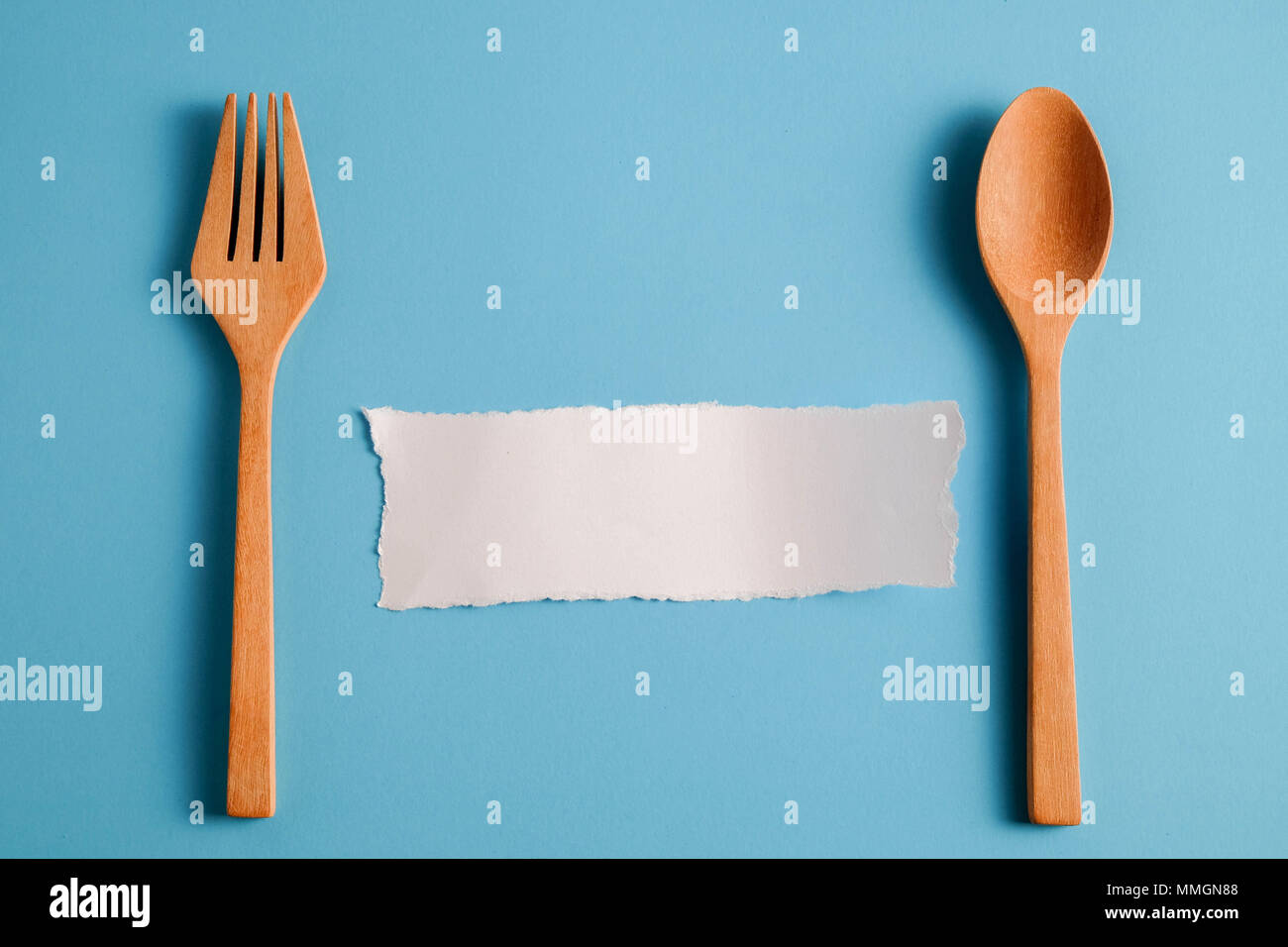 Wooden spoon and white paper on a blue background, for a food menu ...
