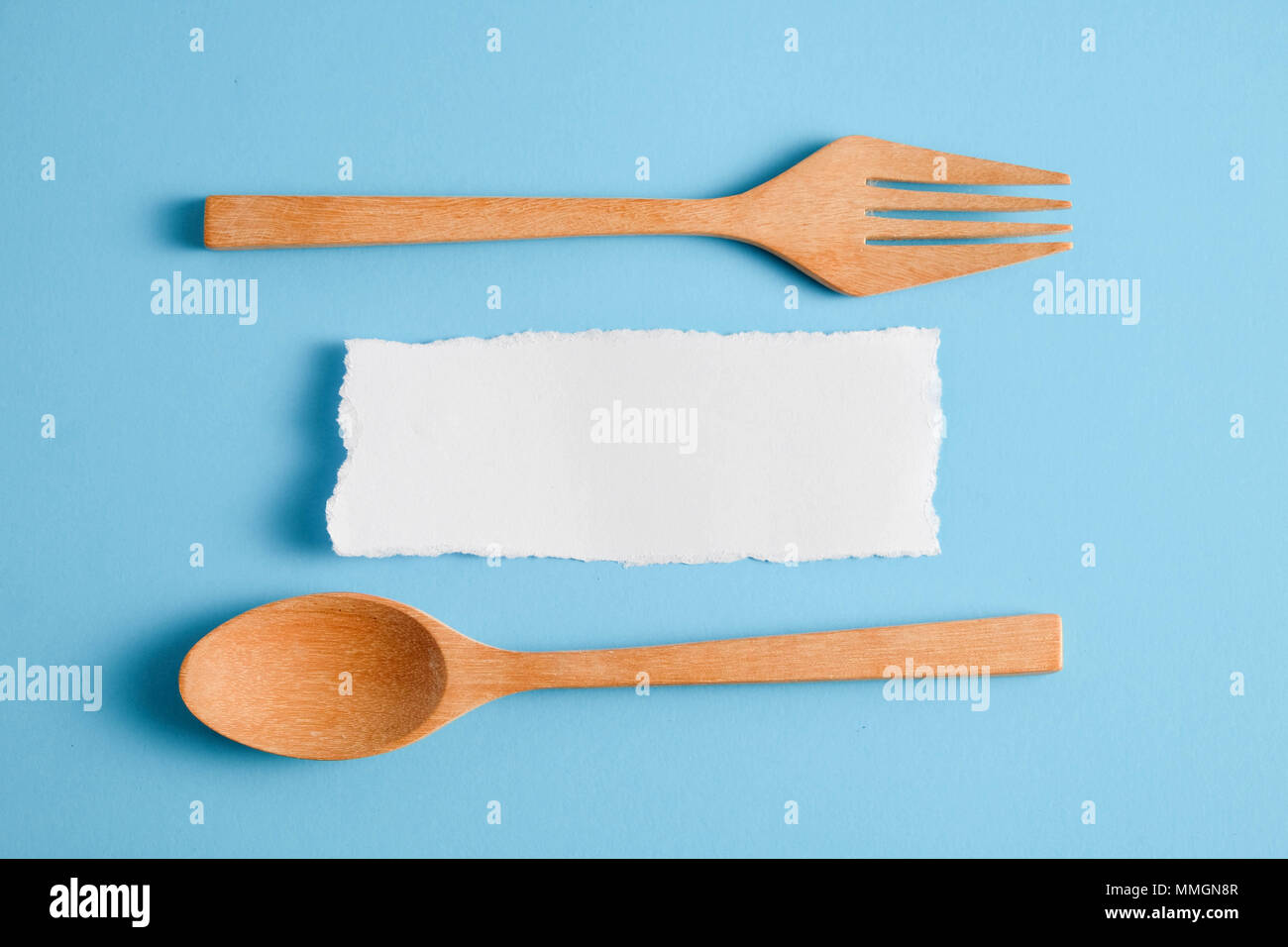 Wooden spoon and white paper on a blue background, for a food menu ...