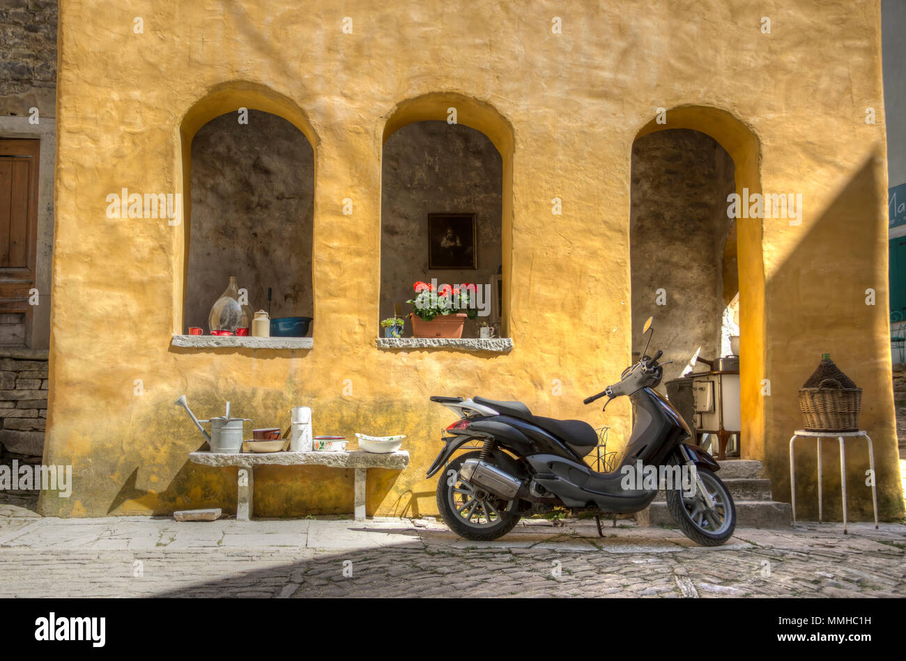 Central Istria, Croatia, April 2018 - Scooter parked in front of an old yellow house at the corner of two streets in the ancient town of Oprtalj Stock Photo