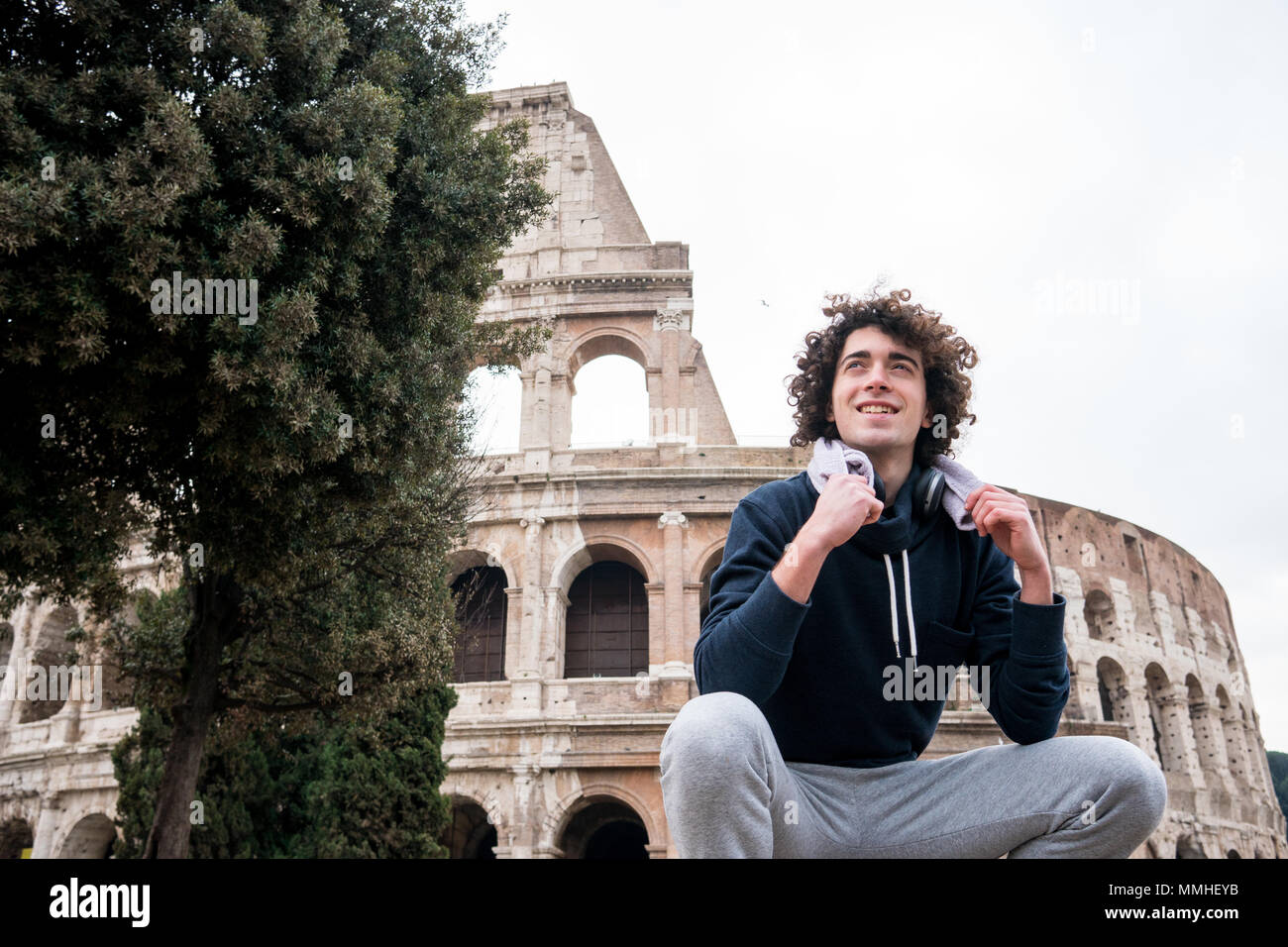 Handsome young sportsman relaxing after training with a towel around his neck in front of Colosseum in Rome Stock Photo