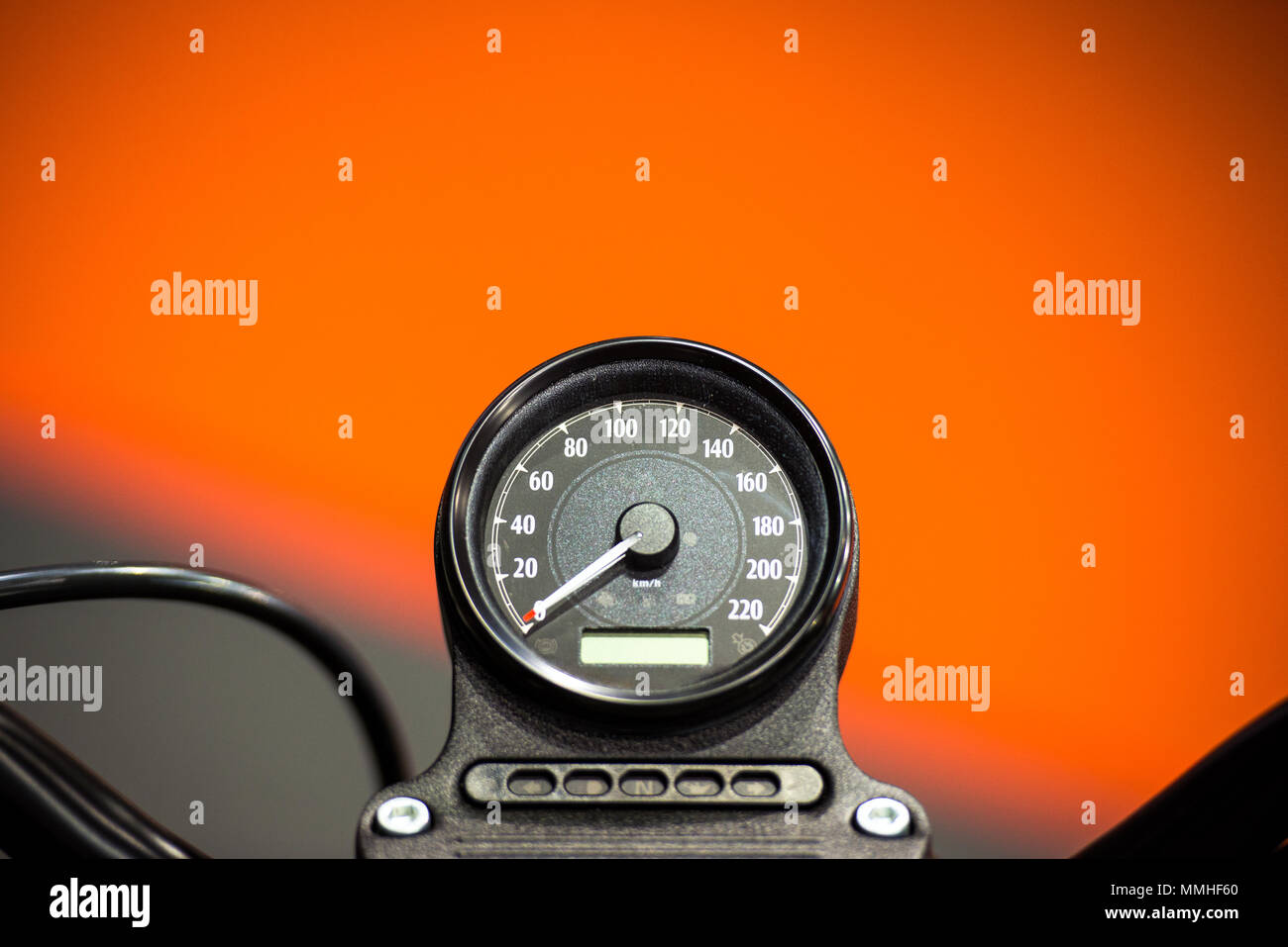 Motorcycle speedometer on dashboard showing kilometers per hour speed on orange background Stock Photo