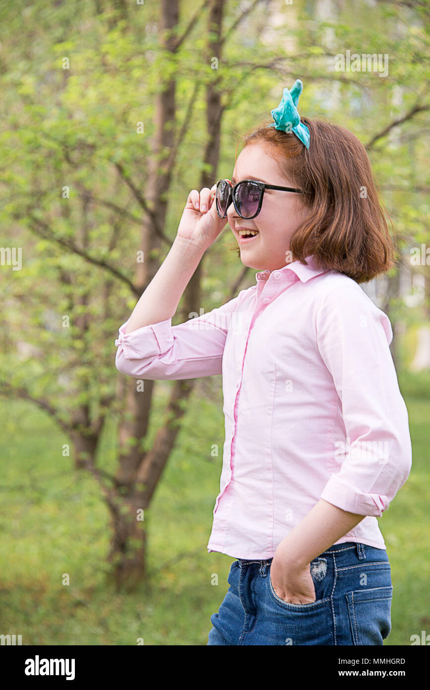 girl in a pink shirt and sunglasses in the nature, smiling and cheering emotionally Stock Photo