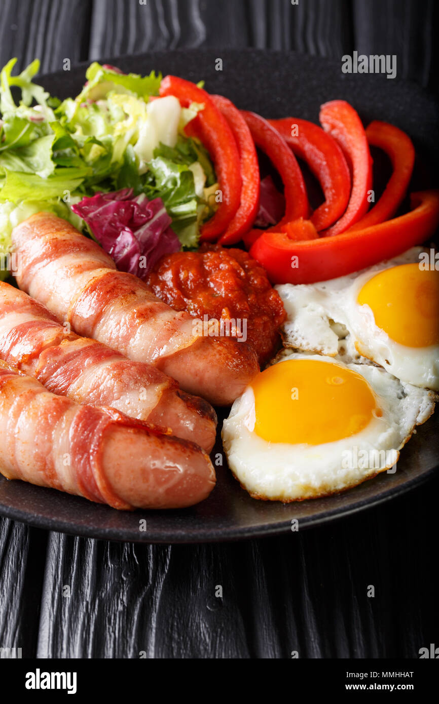 Delicious breakfast of fried sausages wrapped in bacon, eggs and fresh
