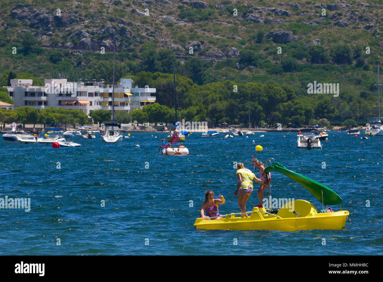 Children on a yellow pedalo in the waters of Port de Pollenca in Mallorca, Spain Stock Photo