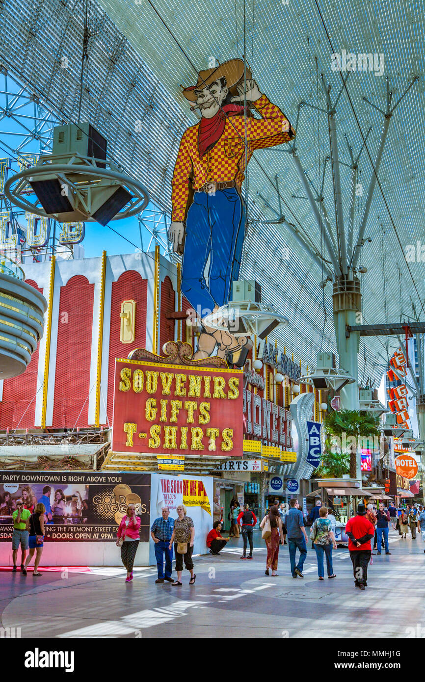 Tourists stroll past Vegas Vic, the 40 foot neon cowboy on top of the Pioneer Club gift shop in Las Vegas, Nevada Stock Photo