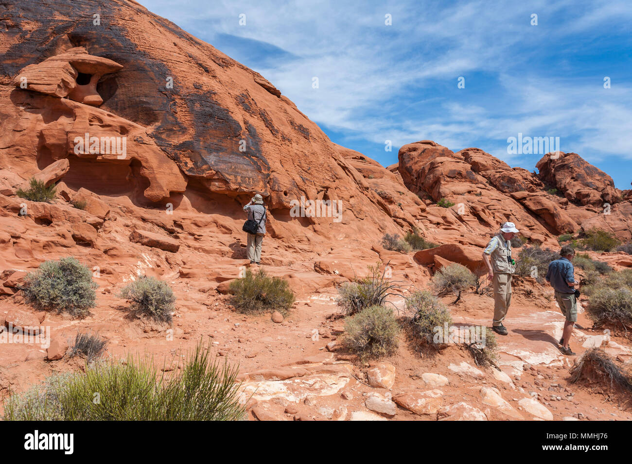 Visitors photographing symbols etched in red sandstone rock formations in the Valley of Fire State Park in Overton, Nevada northeast of Las Vegas Stock Photo