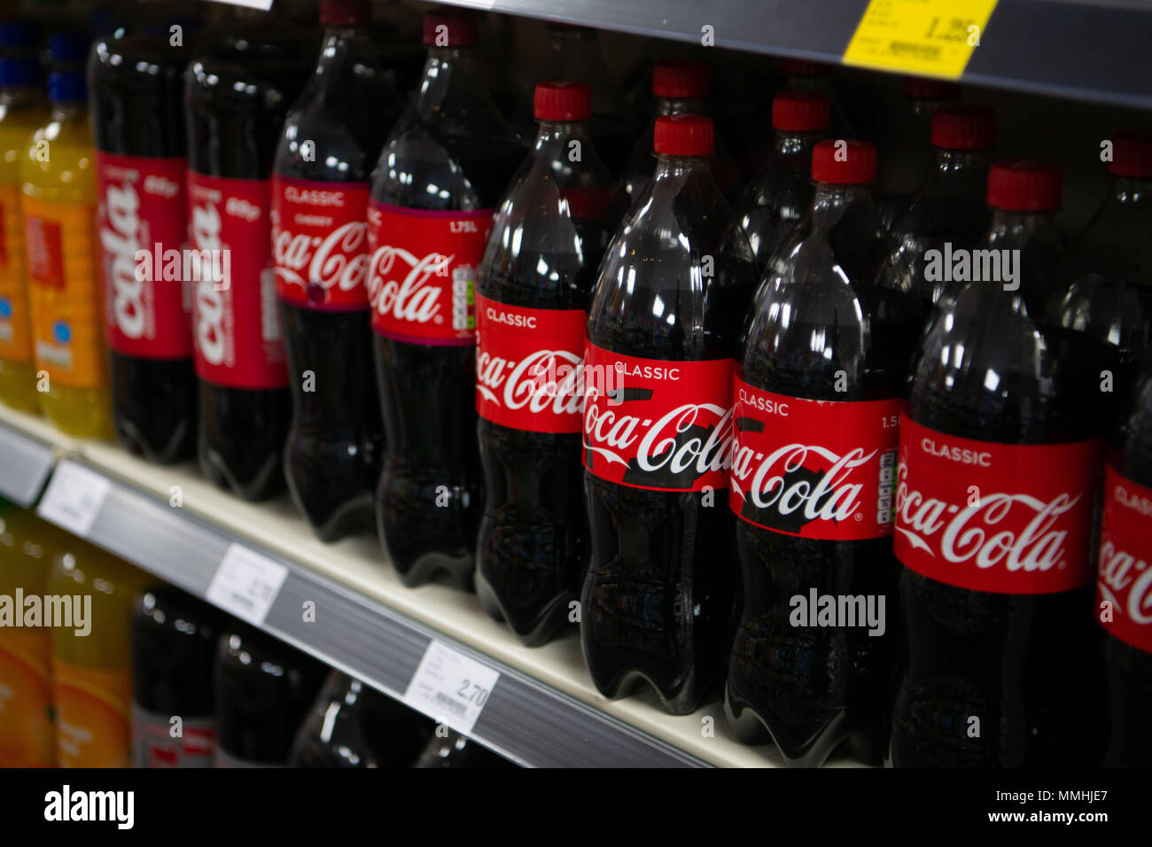 Bottles of Coca Cola fizzy drinks on display on a supermarket shelf