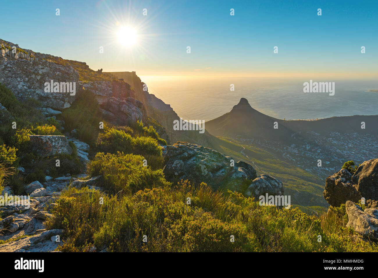 Sunset landscape with sunbeam of Cape Town city and Lions Head mountain peak at sunset seen from the Table Mountain national park, South Africa. Stock Photo