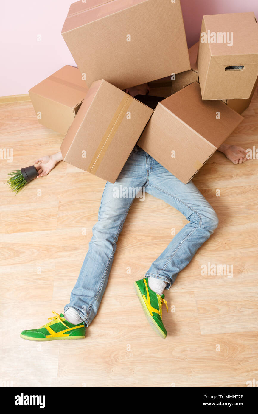 Photo of man in jeans lying under cardboard boxes Stock Photo Alamy