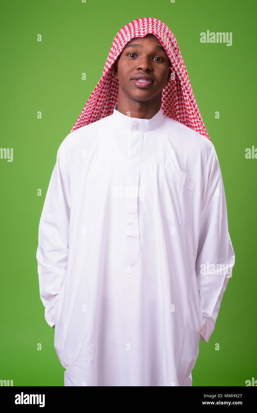 Young African man wearing traditional Muslim clothes against gre Stock Photo