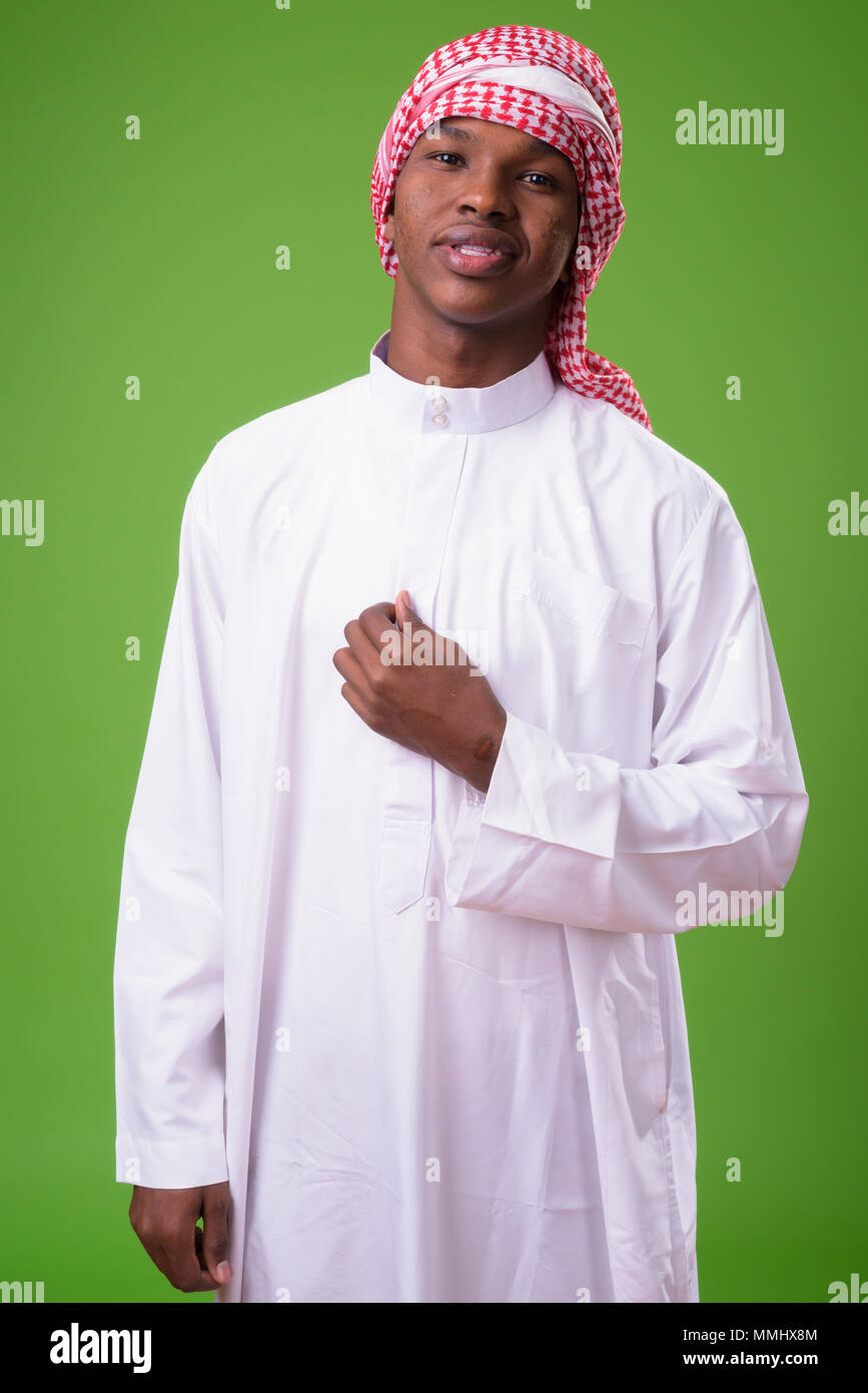 Young African man wearing traditional Muslim clothes against gre Stock Photo
