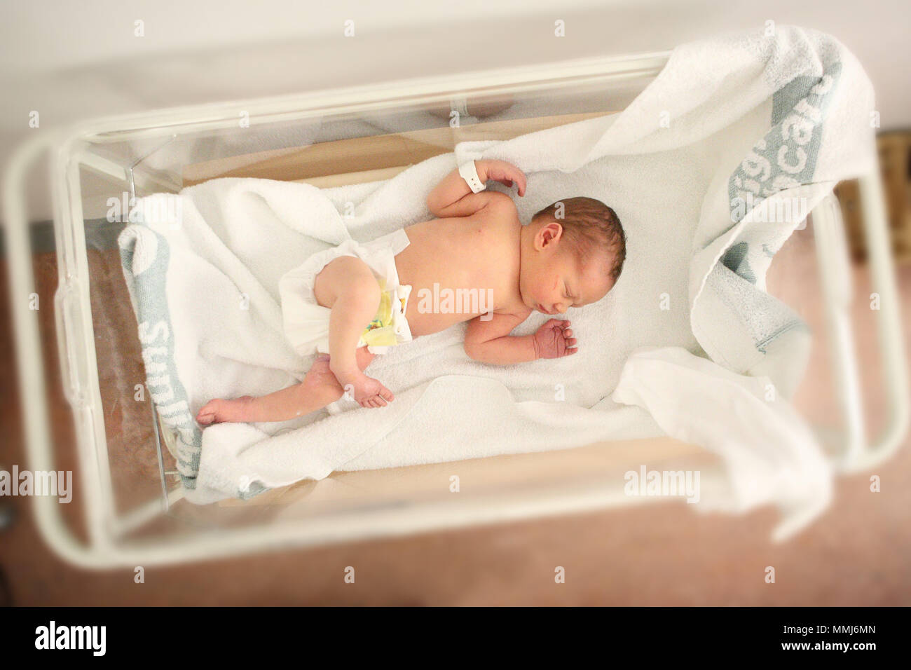 A New Born Baby Sleeps Happily In A Hospital Crib Stock Photo