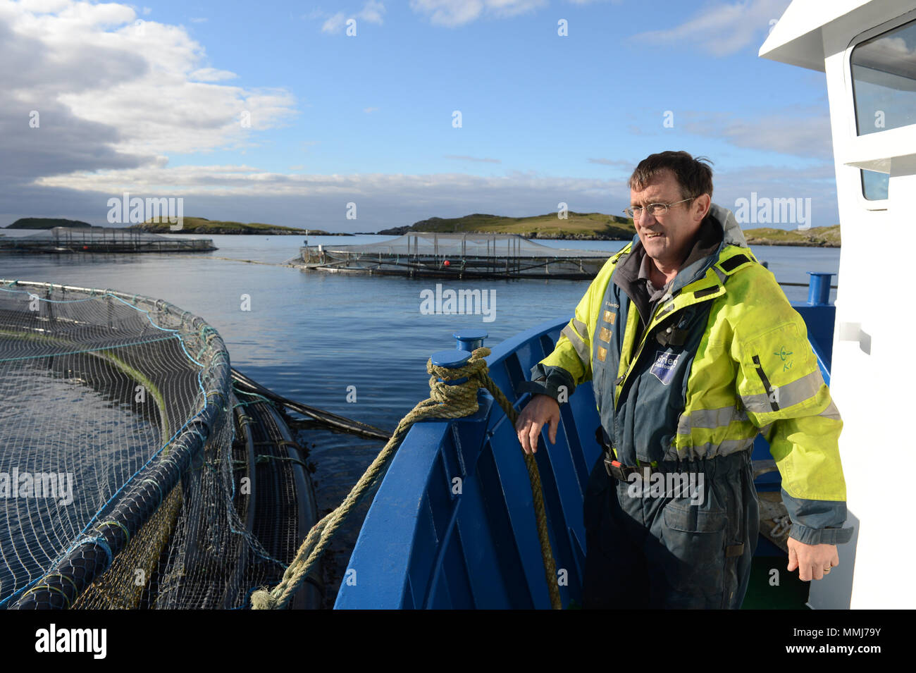 Salmon farmer on a salmon boat tying it up to cages before feeding the fish in the cages Stock Photo