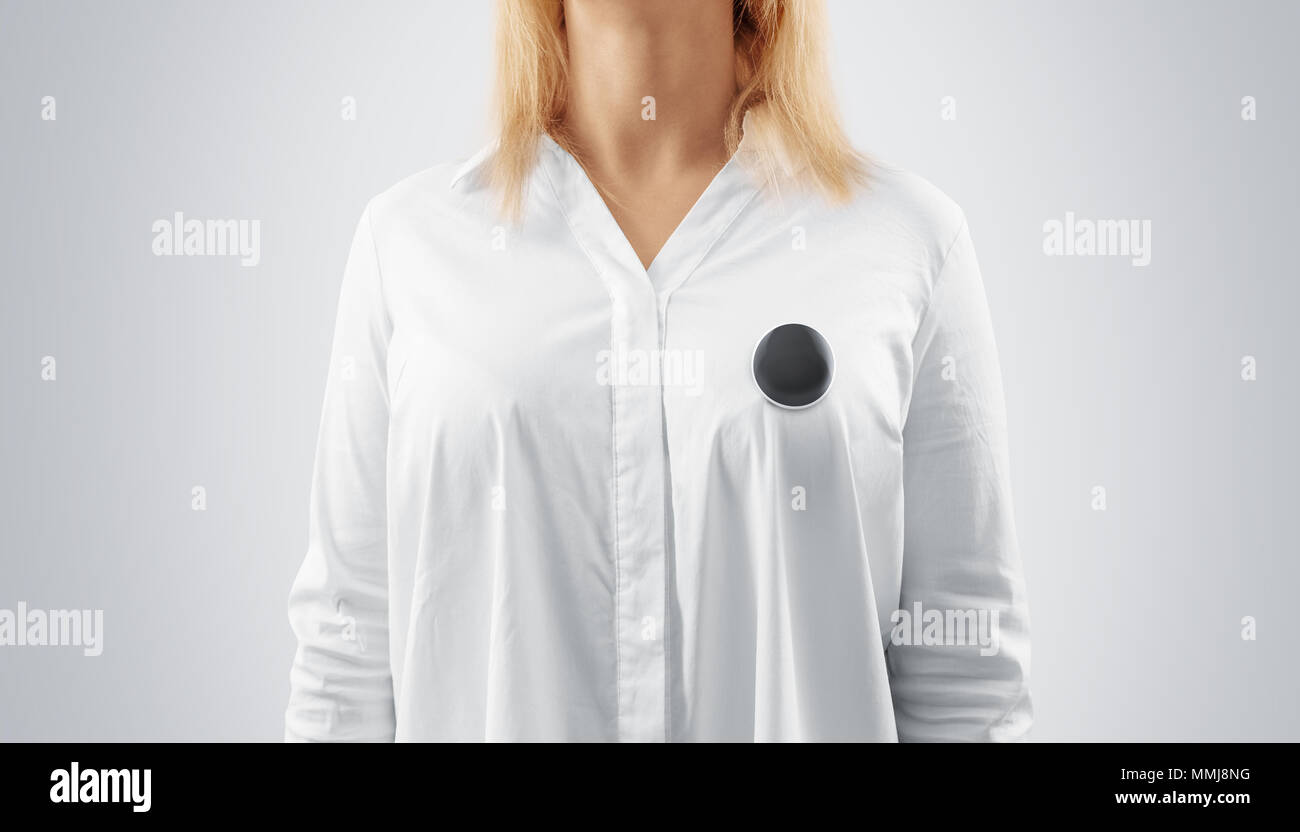 Blank black button badge mockup pinned on the womans chest, close up view. Girl wear white shirt and grey campaign pin mock up. Volunteer round emblem design element. Person with voting symbol Stock Photo