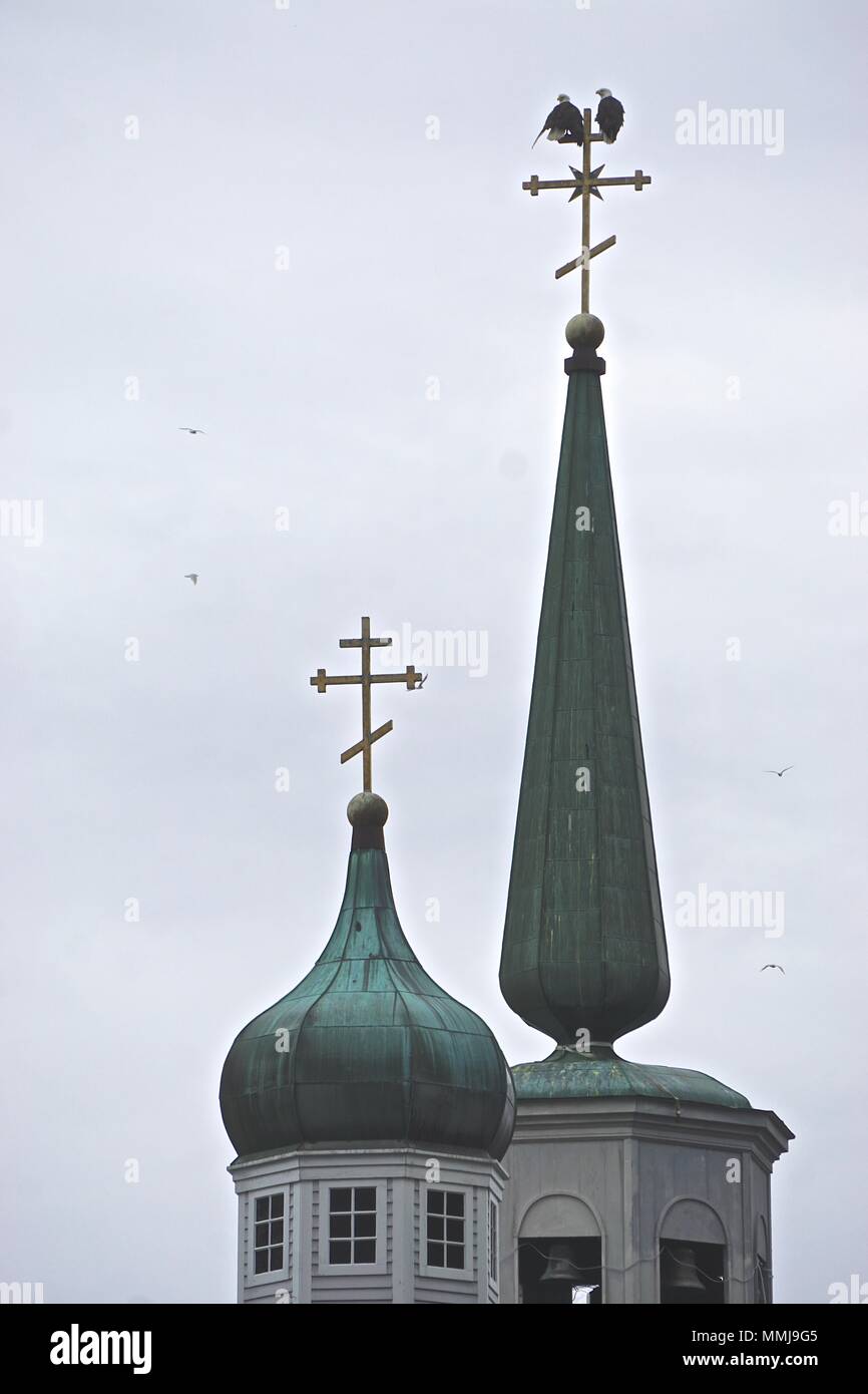 Sitka, Alaska, USA: Two bald eagles (Haliaeetus leucocephalus) perched on the top of the spire of St. Michael’s Cathedral. Stock Photo