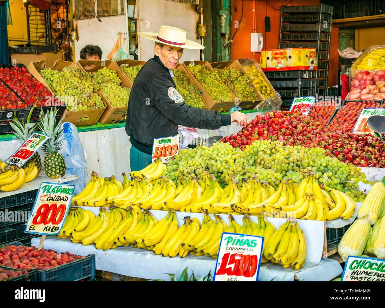 Old man selling bananas, strawberries and grapes wearing traditional Chilean straw hat, Patronata fruit and vegetable market, Santiago, Chile Stock Photo