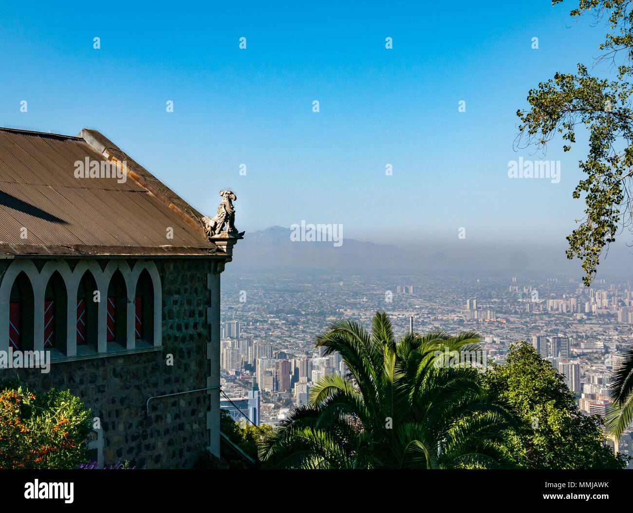 View over city skyline  from San Cristobal hill, Santiago, Chile with smog visible and gargoyle on old church hilltop building Stock Photo