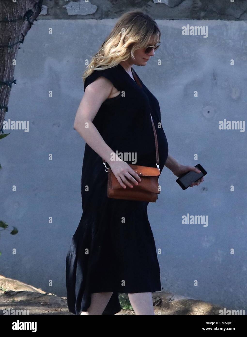 Kirsten Dunst shows her baby bump in a black sundress Featuring
