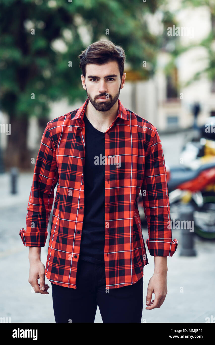 Young bearded man, model of fashion, standing in urban background wearing  casual clothes. Guy with beard and modern hairstyle in the street with plaid  Stock Photo - Alamy