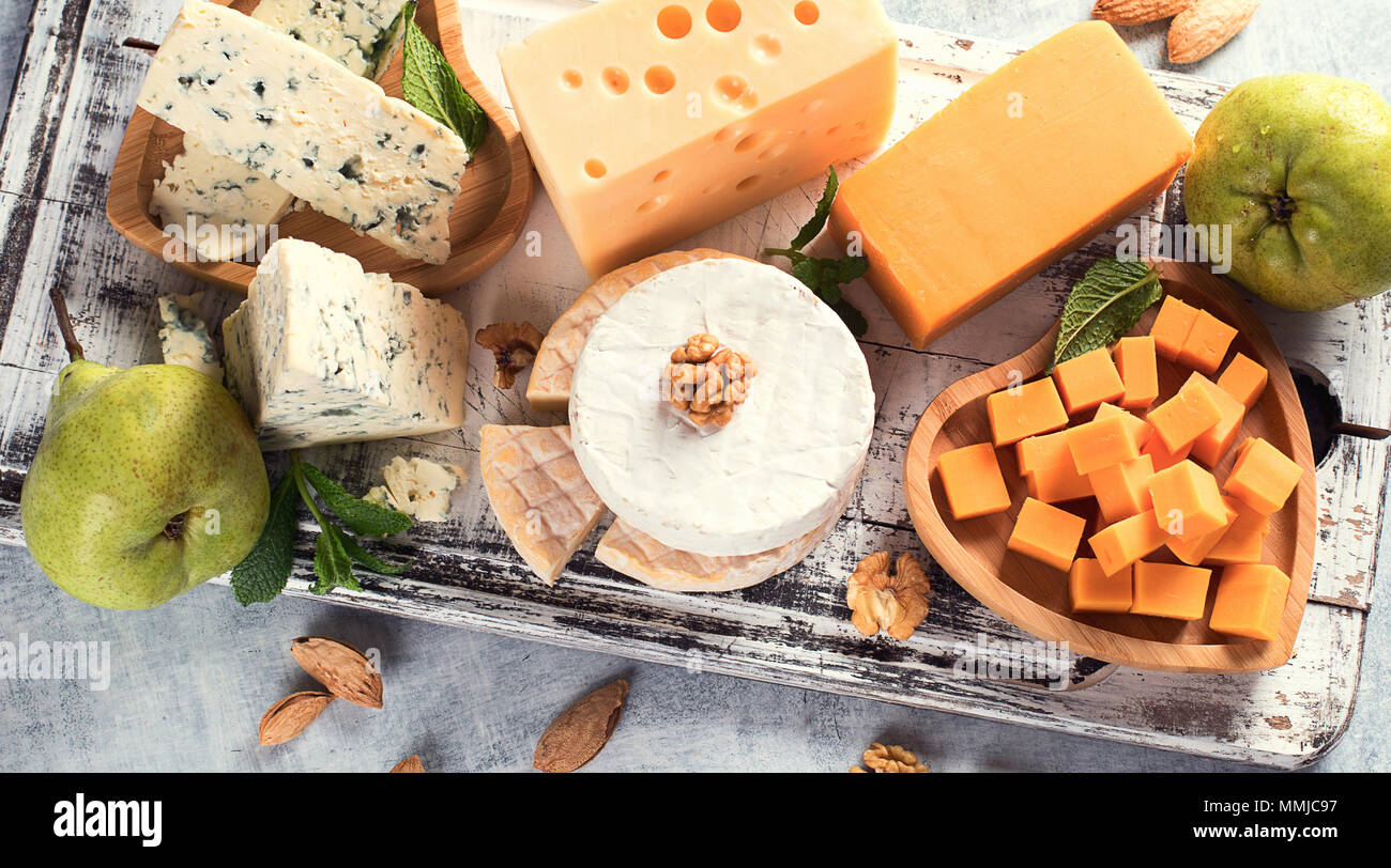 Different kinds of cheeses on rustic wooden board. Stock Photo