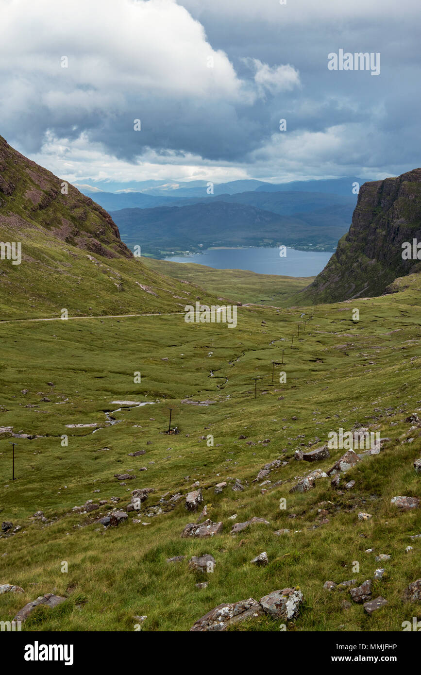 Cyclist making the ascent of Bealach na BÃ  pass to Applecross. A tiny dot in the big landscape. Loch Kishorn in the background. Stock Photo