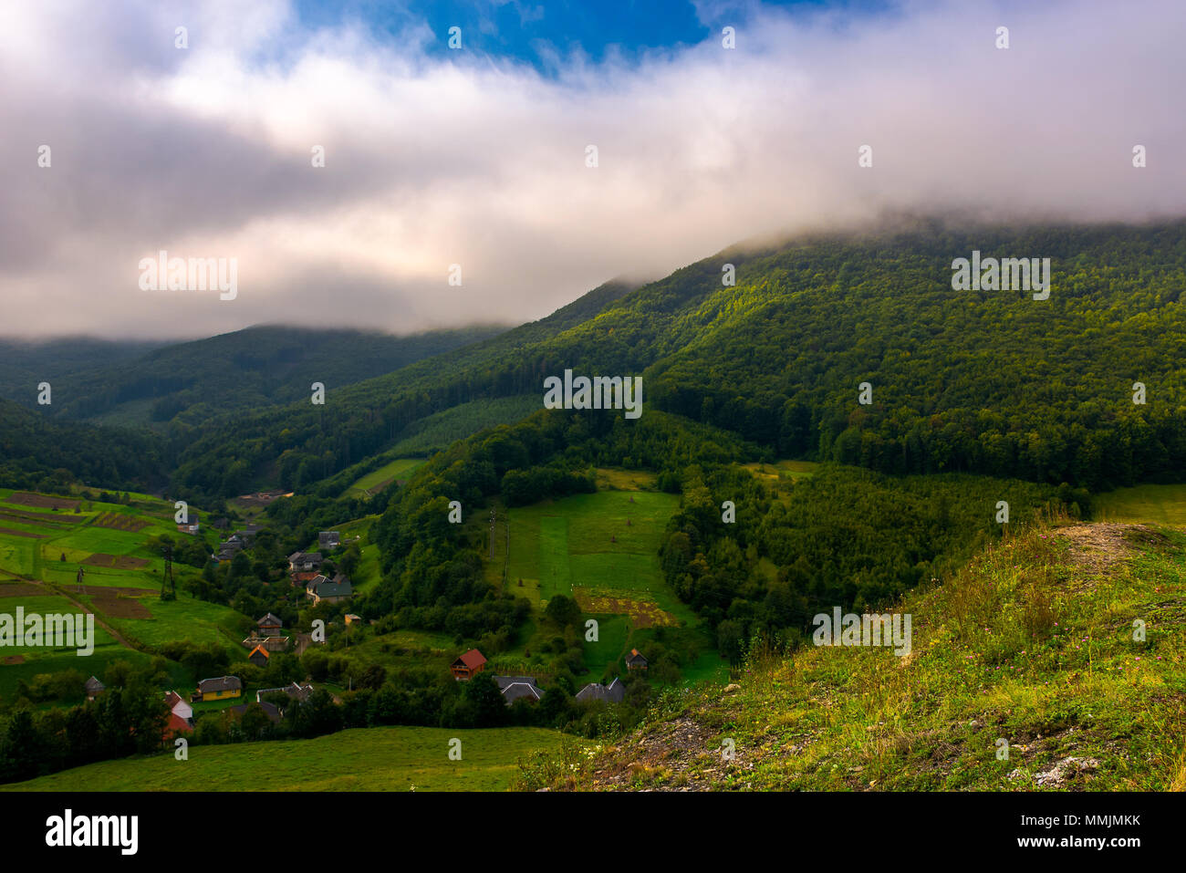 small Carpathian village in mountains. beautiful landscape with forested hills and agricultural fields on a cloudy morning Stock Photo