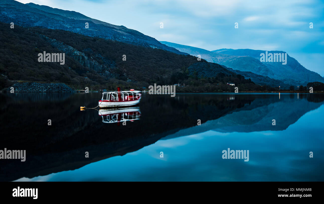 White boat and mountain reflections on Llyn Peris in Snowdonia National Park, Wales Stock Photo