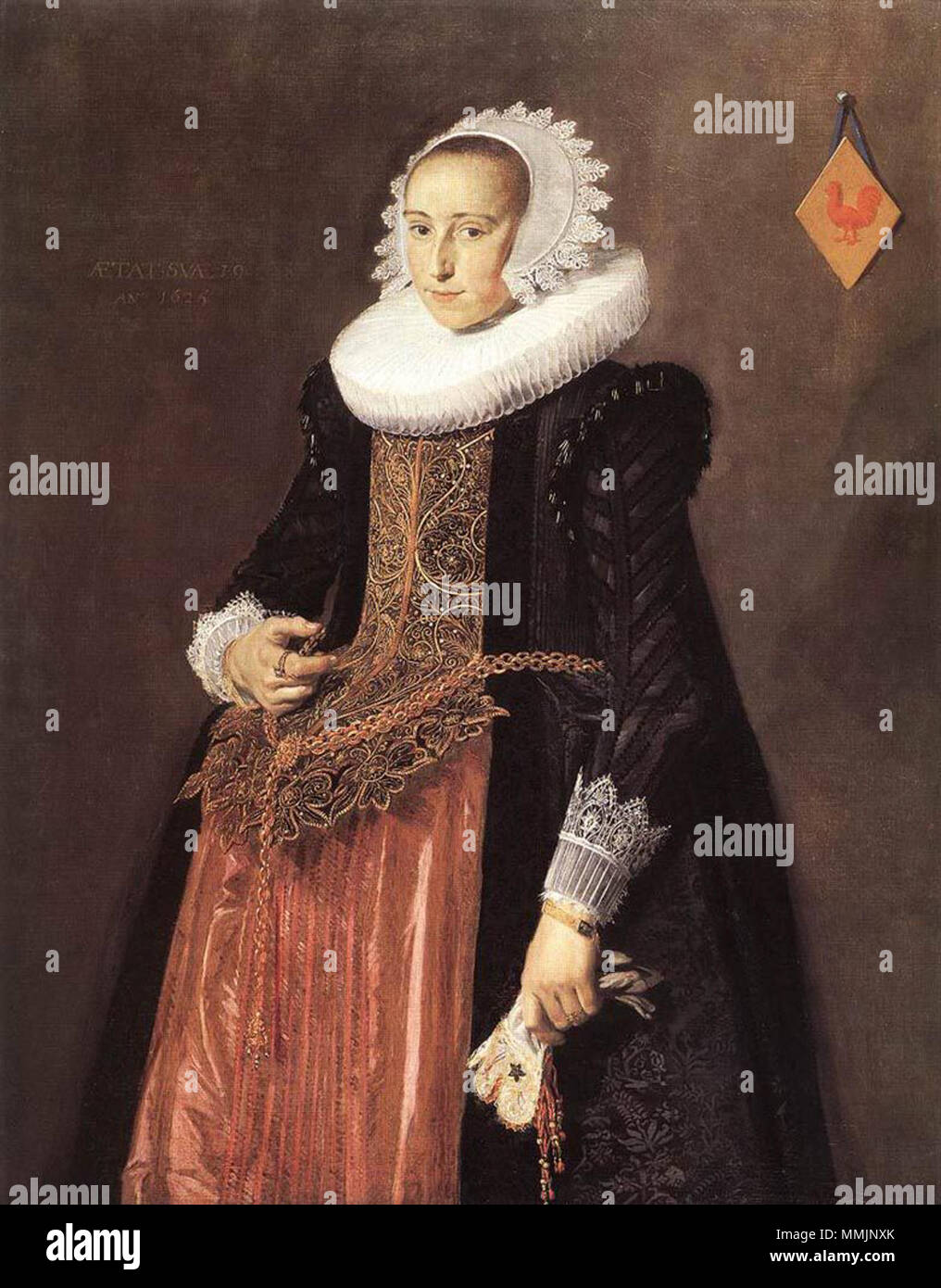.  Portrait of Aletta Hannemans, who married Jacob Pietersz Olycan in 1624 and Nicolaes van Loo in 1640. She is shown three-quarters-length, standing, turned three-quarters left, looking at the spectator. She wears a costly bridal stomacher called a 'bruidsborst', worked with gold thread and showing various flowers. She wears it over a colorful purple and red skirt that is draped over a French fardegalijn, which supports the heavy gold chain wrapped around her gown and through her 'vlieger'. Her vlieger is edged with black velvet and shows off her stomacher and skirt. Her sleeves are attached  Stock Photo