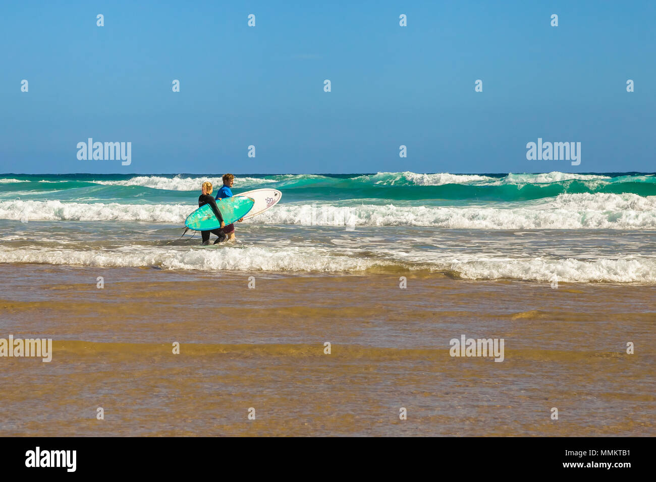 Phillip Island, Victoria, Australia - January 4, 2015: Two surfers holding surfboards at Woolamai Beach, Cape Woolamai State Faunal Reserve in summer Stock Photo