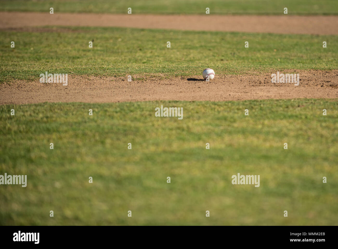 Baseball casting long shadow on the dirt of the field pitching mound. Stock Photo