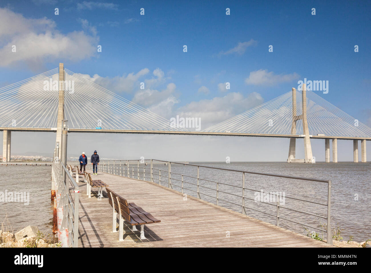 2 March 2018: Lisbon, Portugal - Two men out for a walk on the boardwalk near Vasco da Gama Bridge, the 17km cable stayed bridge which spans the River Stock Photo