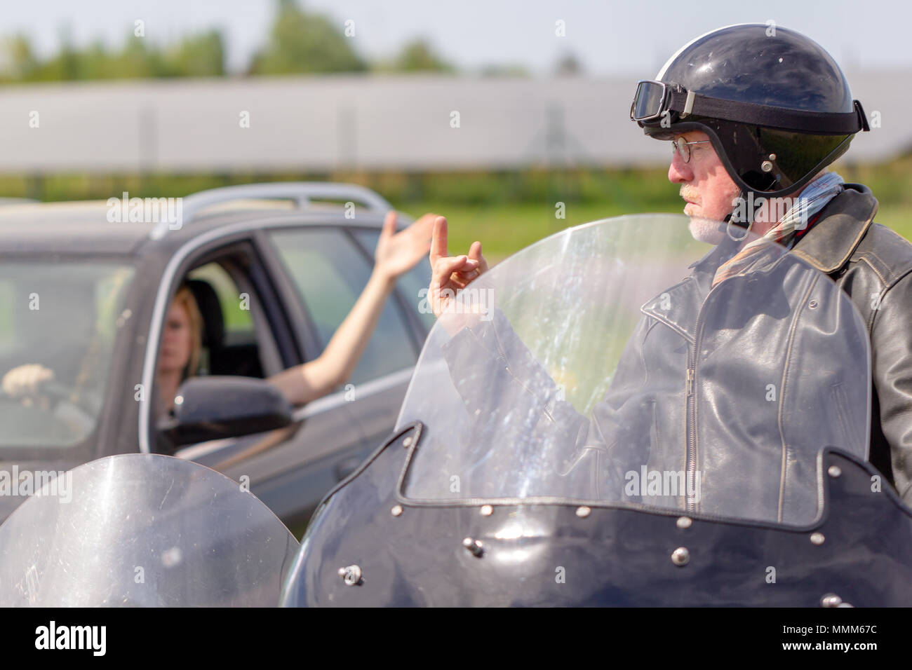 a biker shows his middle finger to a car driver Stock Photo