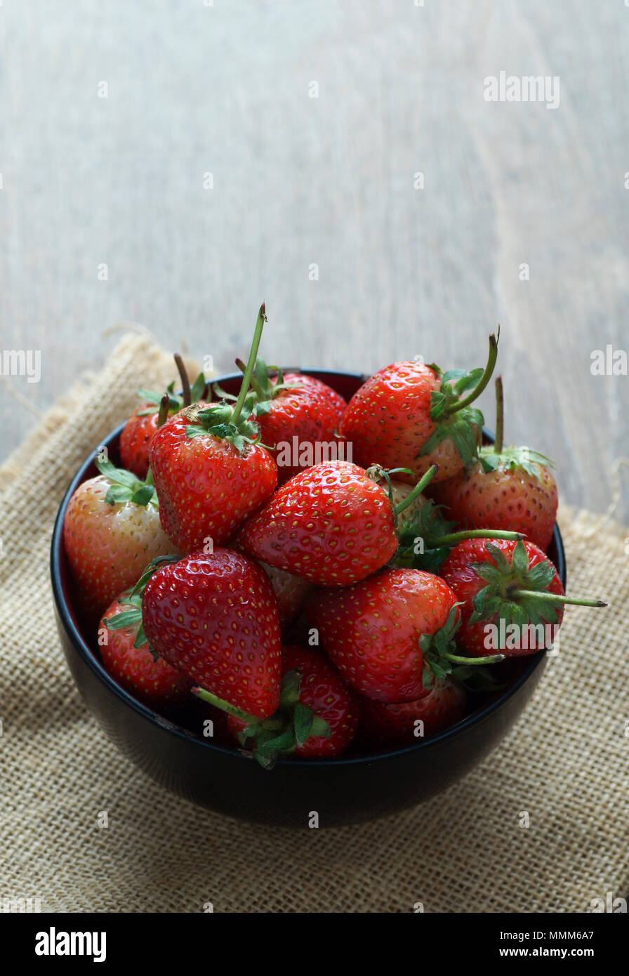 Fresh strawberries in a bowl on wooden table with low key scene Stock ...