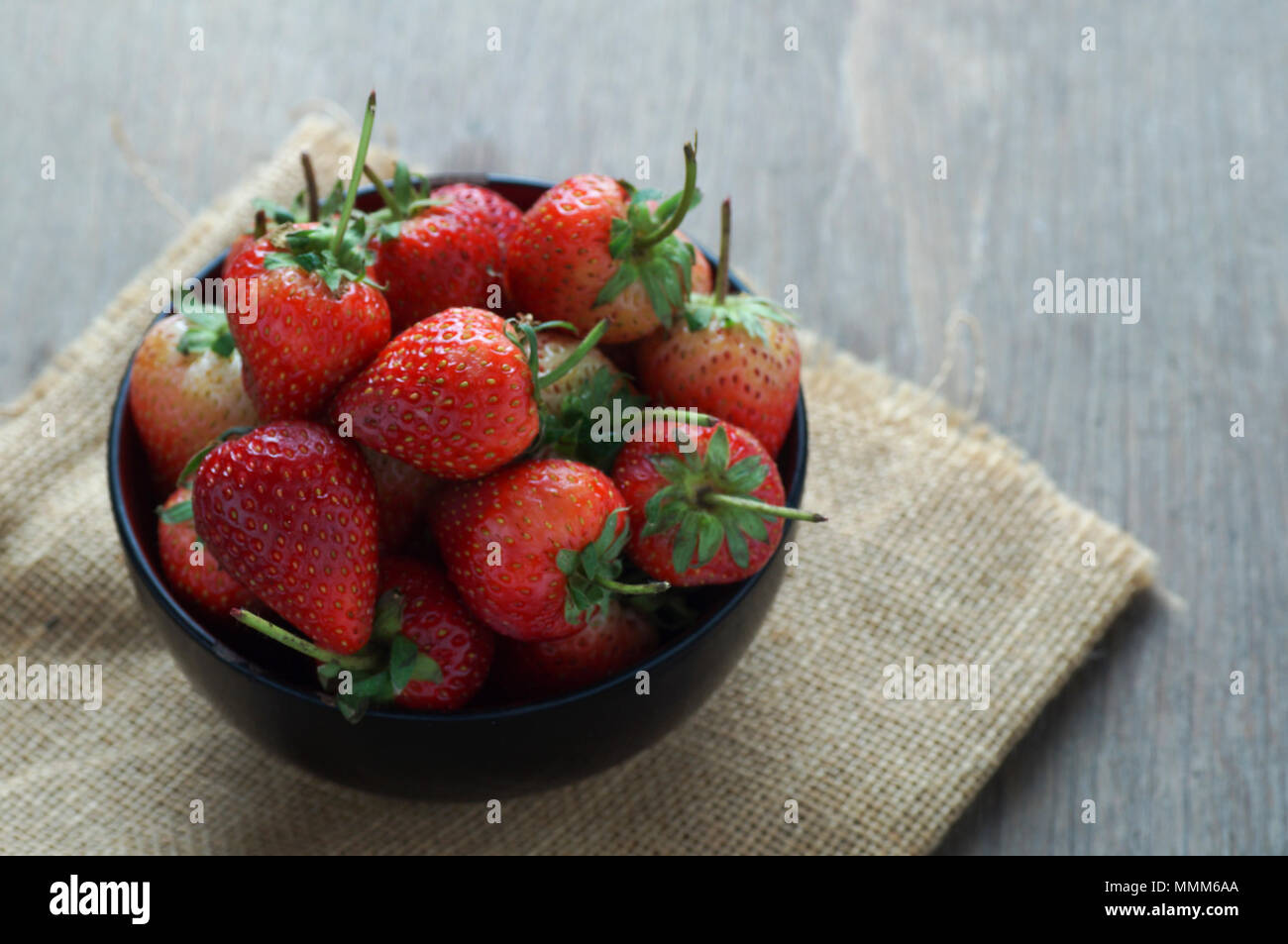 Fresh strawberries in a bowl on wooden table with low key scene Stock ...