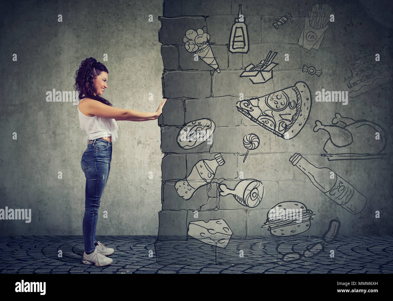 Side view of a motivated young woman resisting temptation of eating fast foot and choosing better diet. Stock Photo