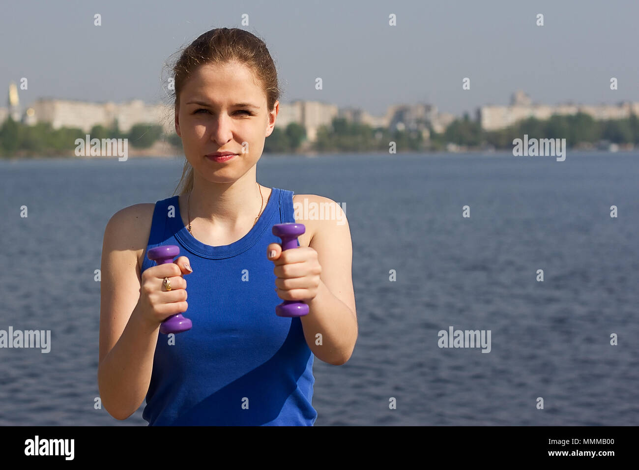 Young woman with weights exercising in the nature Healthy lifestyle and fitness concept Stock Photo